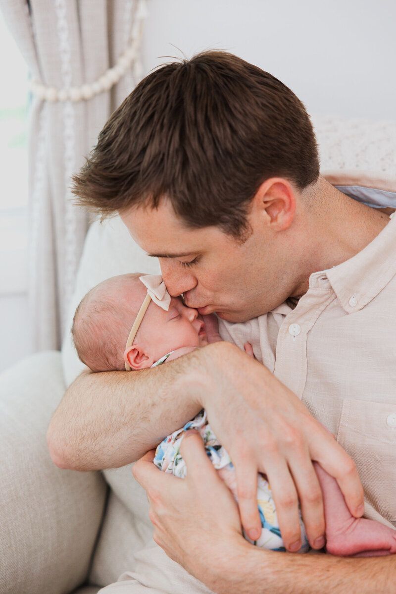 Gentle close-up moments between parent and baby on beige couch.