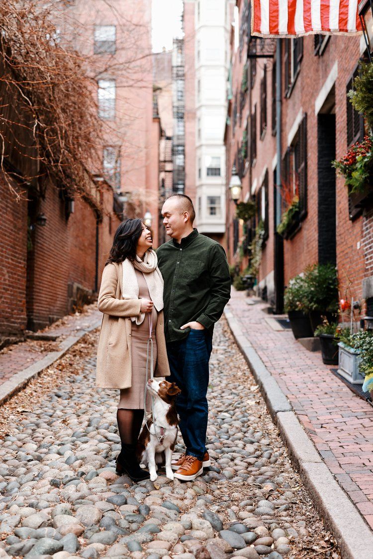 A couple in winter coats shares a romantic moment on a historic cobblestone street in Boston's Beacon Hill neighborhood.