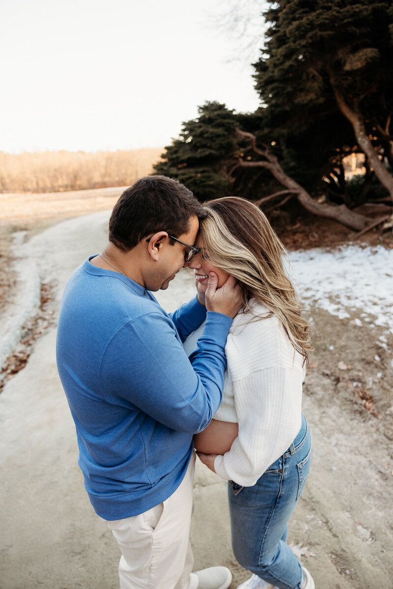 Couple in blue and white embrace during sunset maternity session.
