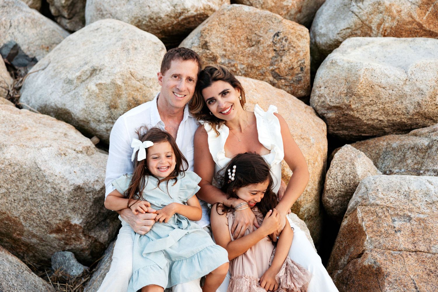 People enjoying a casual outdoor photo shoot on rocky beach terrain at sunset, creating candid moments together.