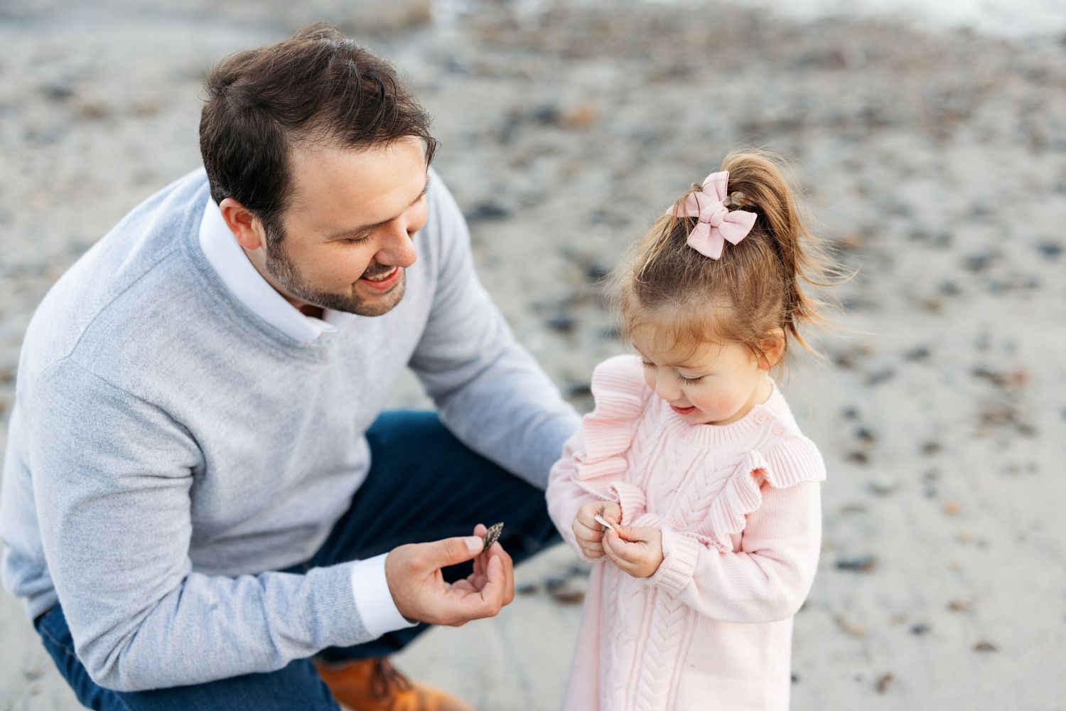 A tender moment shared between parent and child playing on a sandy beach during sunset.