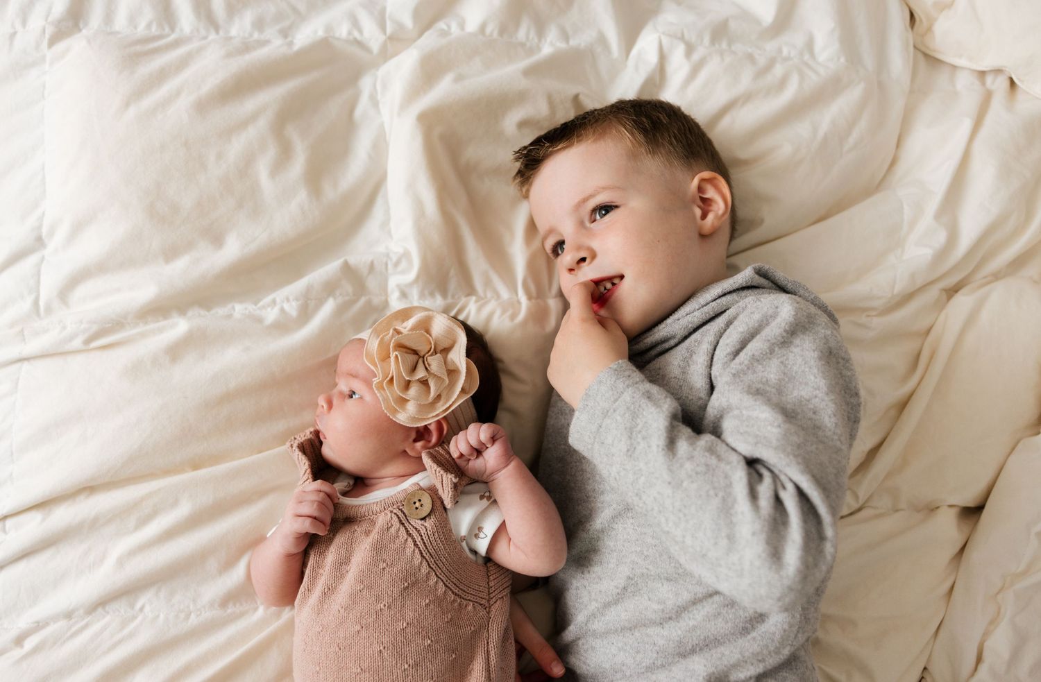 Four candid photos show a sleeping baby in different poses on white bedding.