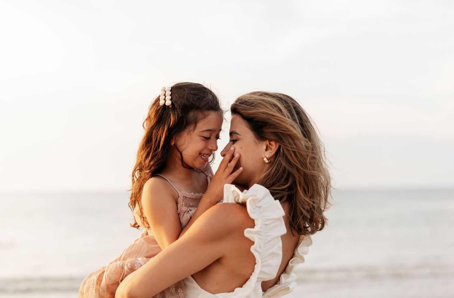 Couple embraces tenderly on a sunlit beach during their outdoor photo session at golden hour.