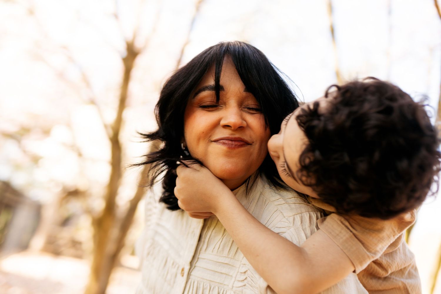 Two people in white embrace and share a joyful moment together outdoors in warm sunlight.
