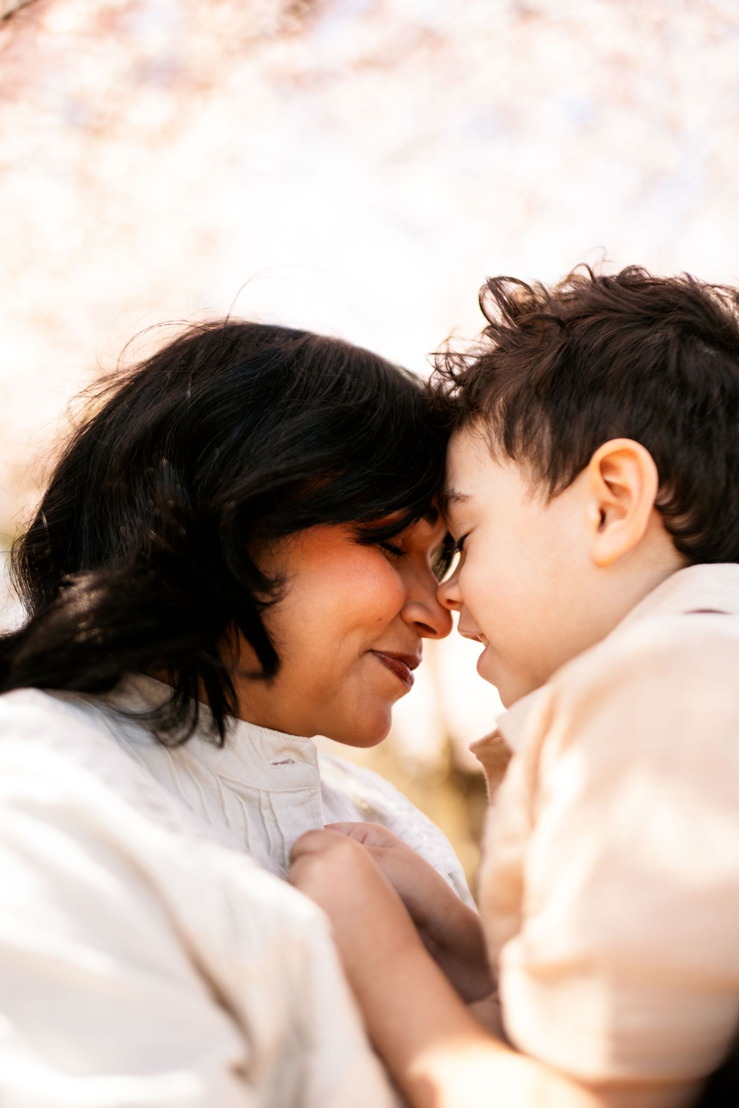 Close-up shot of an intimate moment between mother and child against a soft pink floral backdrop.