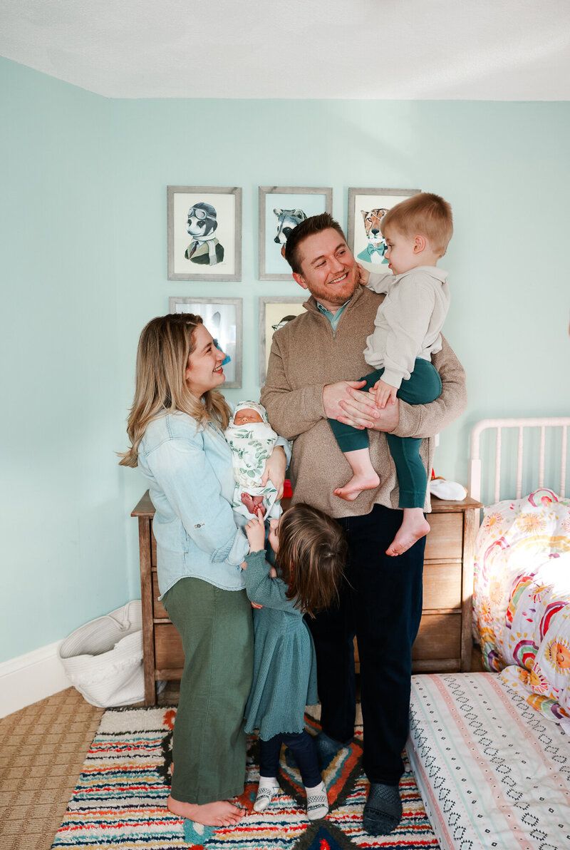 A family shares joyful moments together in a mint green bedroom with decorative wall art.