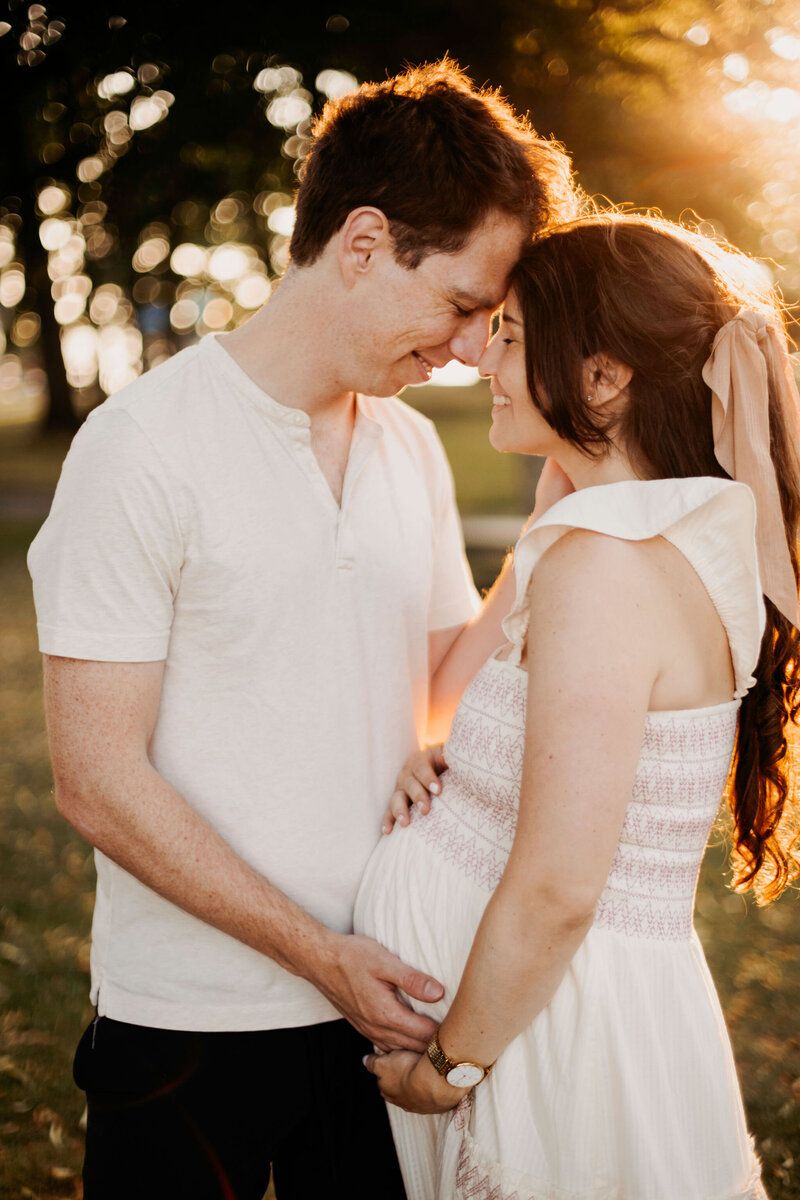 Couple in white outfits sharing intimate moment during sunset photoshoot.