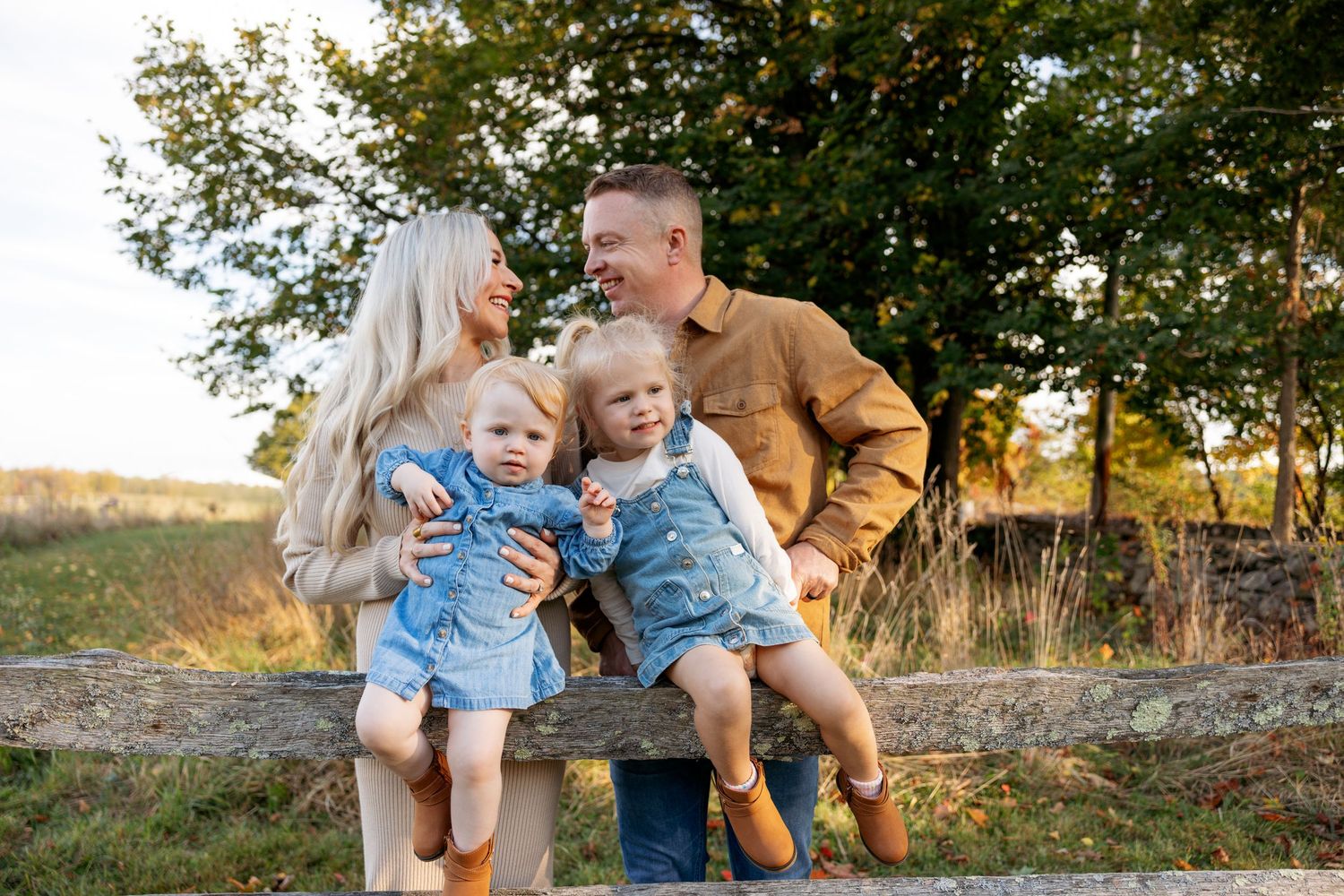 A sweet family moment captured outdoors against a backdrop of trees during golden hour.