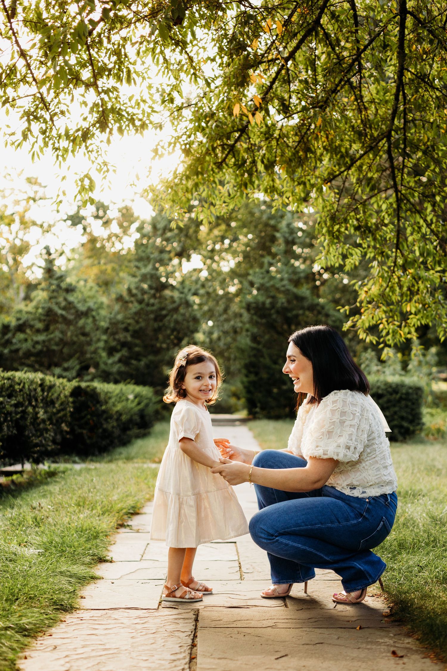 Tender outdoor moment between two people sitting on a stone path surrounded by greenery.