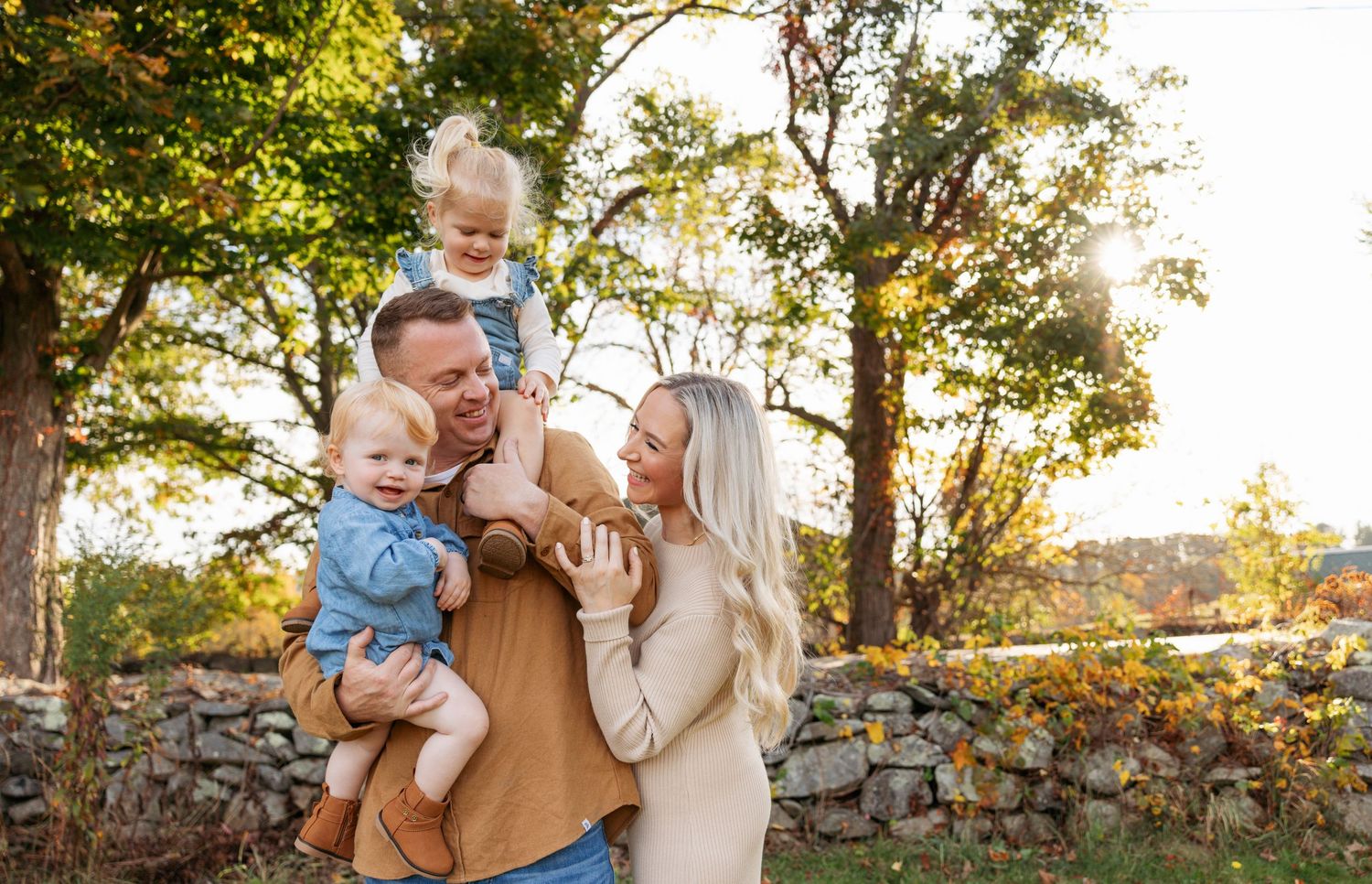 Family spending quality time together by a rustic stone wall during golden hour in autumn.