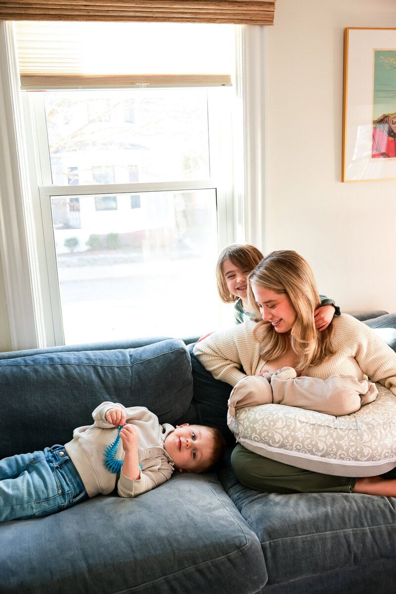 A relaxed family moment on a blue couch by a bright window.