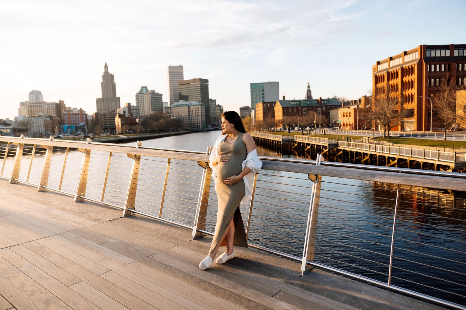 Urban waterfront boardwalk with city skyline view at sunset.