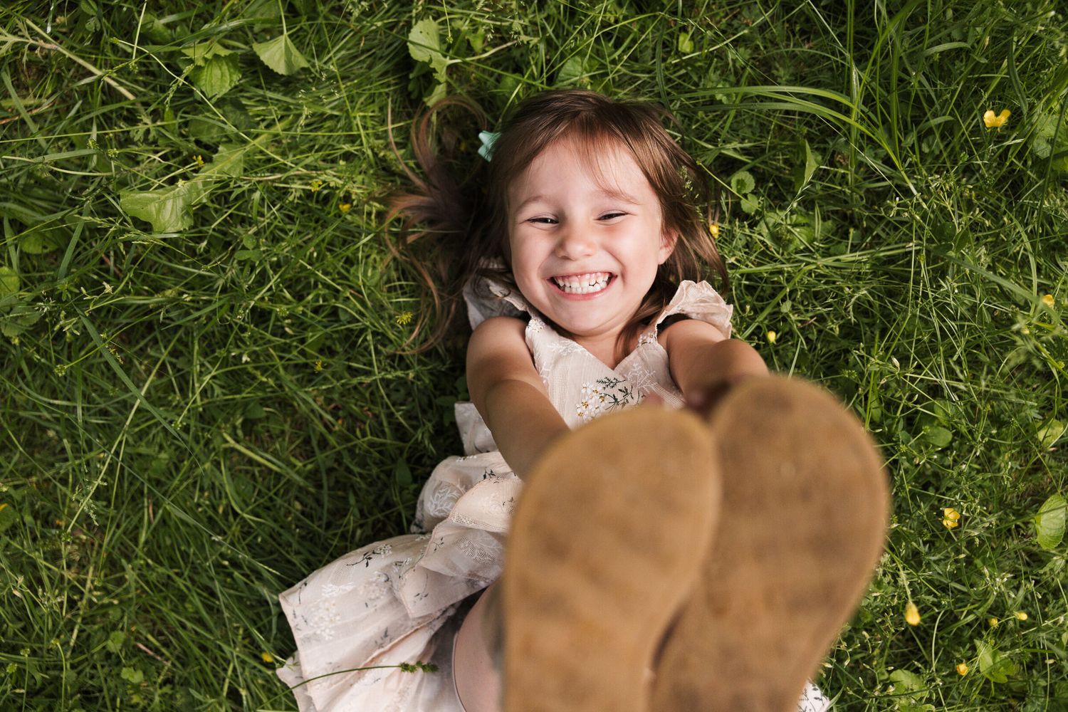 Child laying in green grass with joyful expressions.