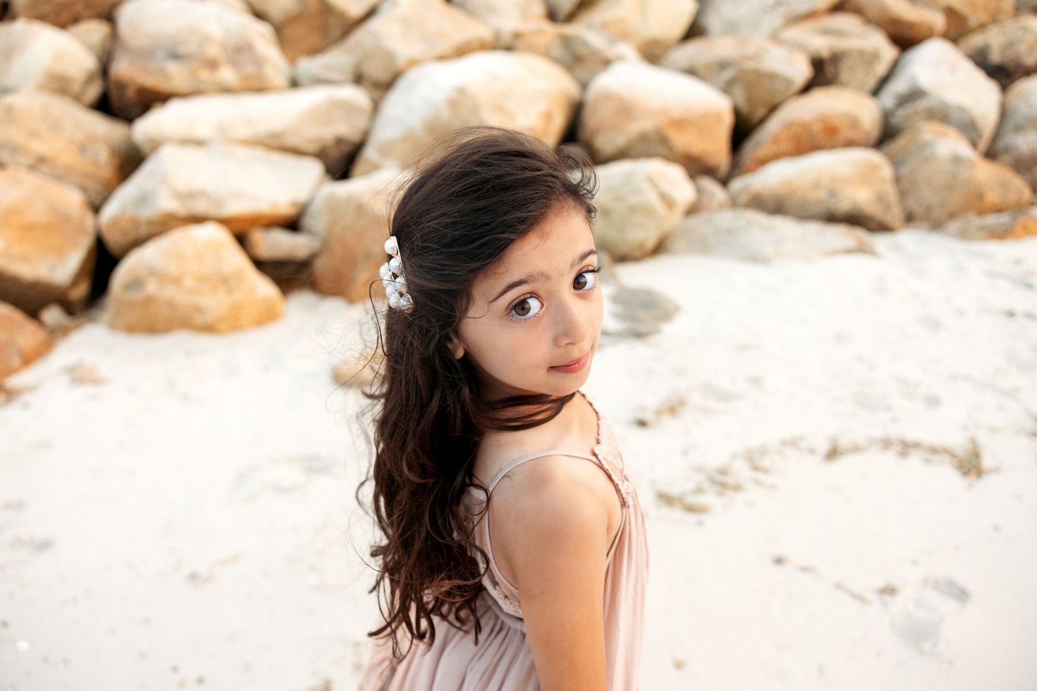 An artistic photo shoot by rock formations captures a casual lifestyle portrait in natural sunlight.