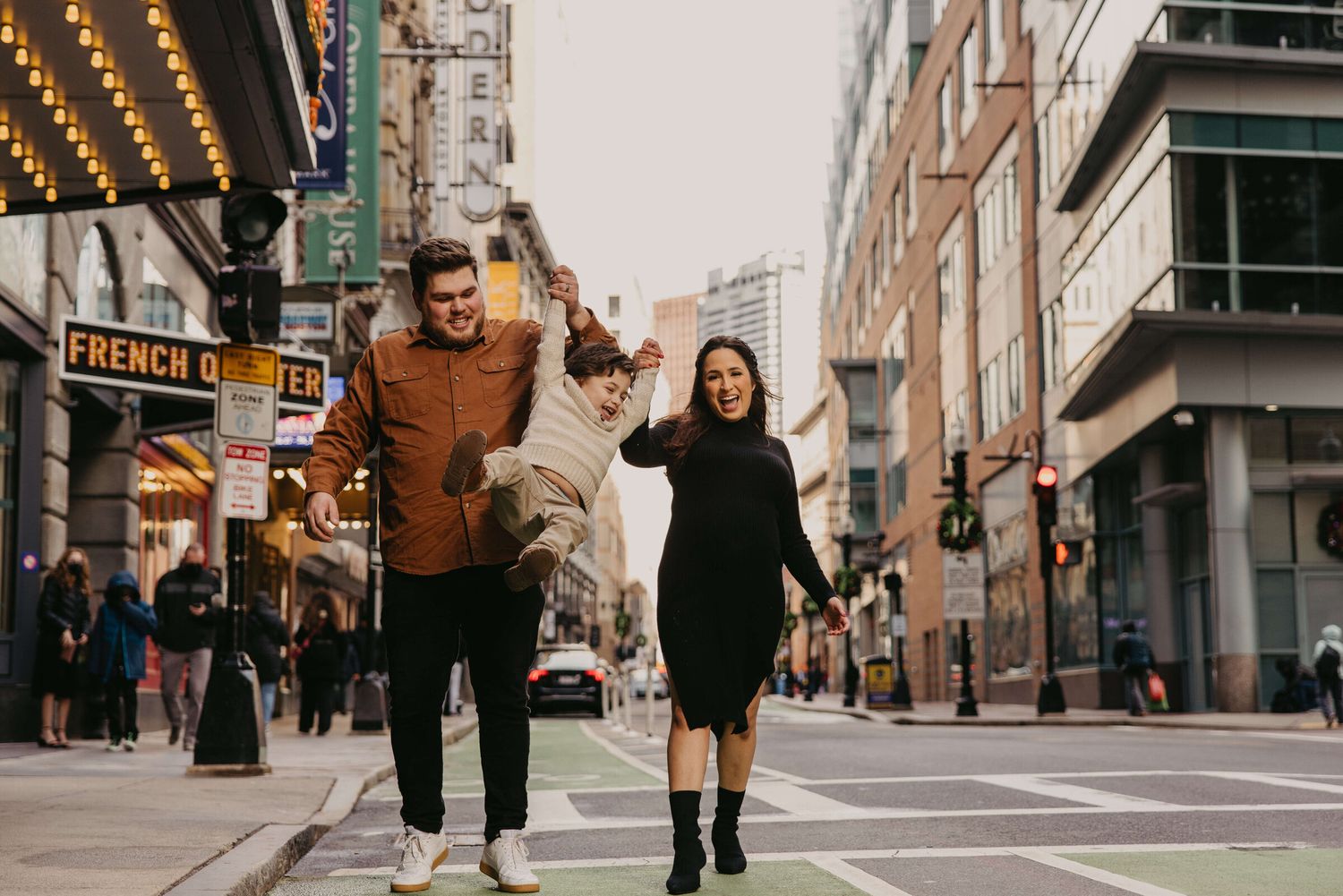 Romantic couple poses in city street with decorative fall decor and buildings.