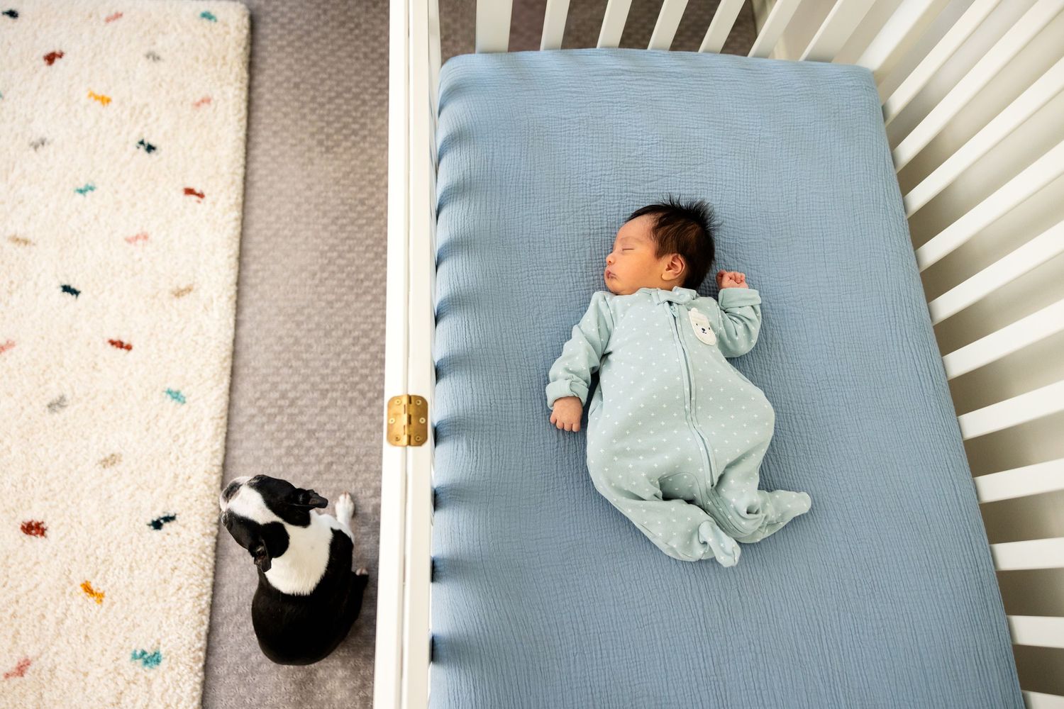 A sleeping baby rests peacefully in a light blue crib.