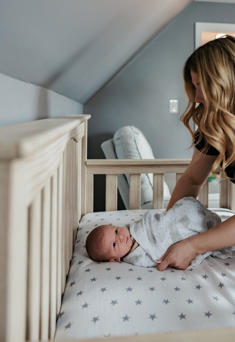 Parent and baby interacting in white nursery with star-patterned bedding.