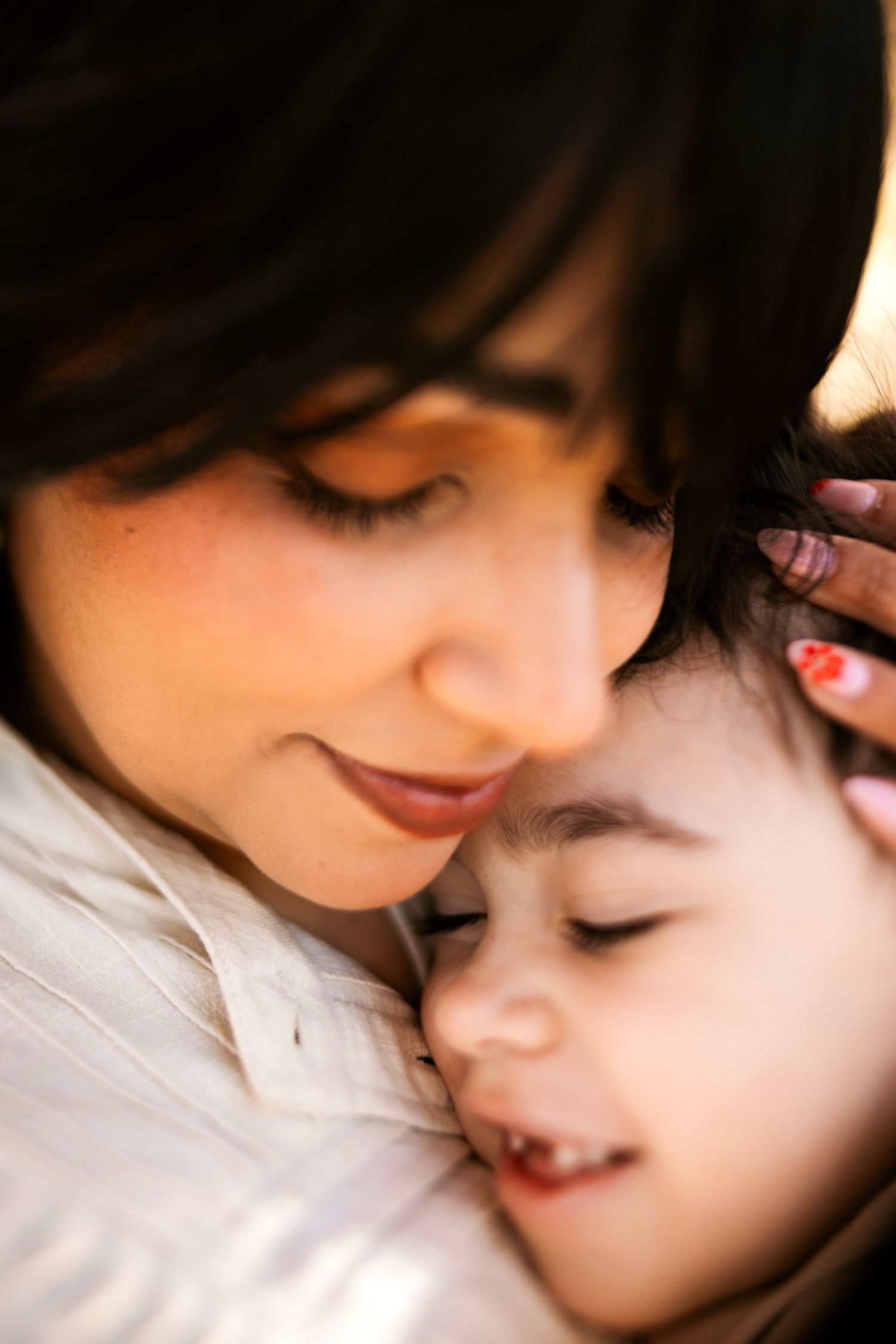 A gentle close-up profile view of two faces resting together in a tender moment against a white background.