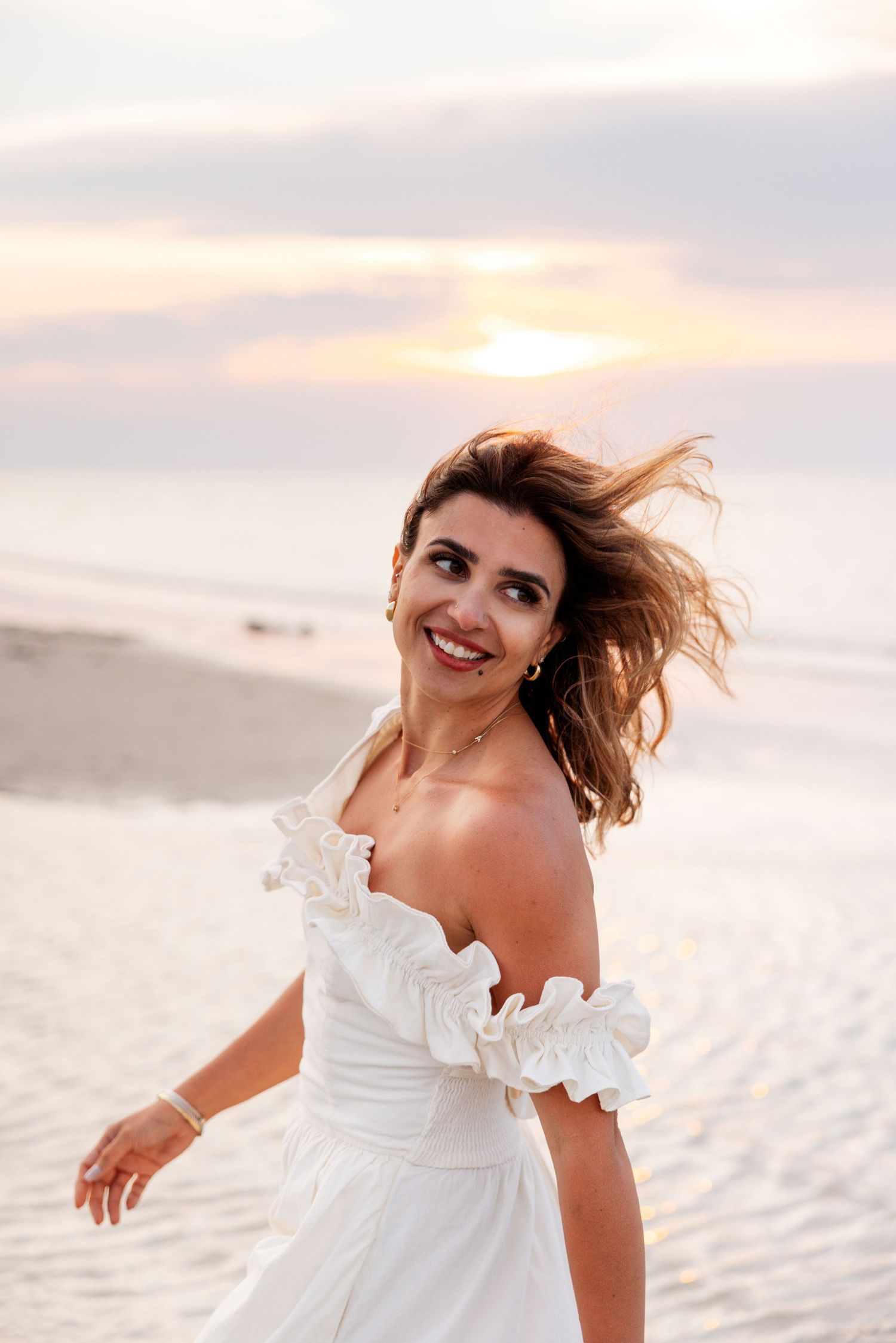 Candid sequence of a white dress beach photoshoot with flowing fabric and natural sunset lighting.