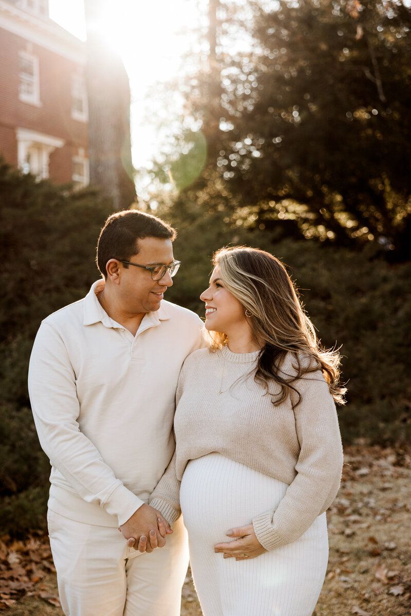 Couple in matching cream outfits sharing an intimate moment in golden sunset light.