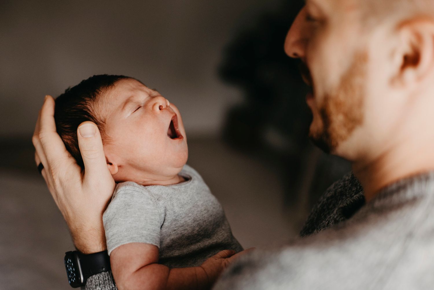 Sweet intimate moment captured between parent and baby in soft lighting.