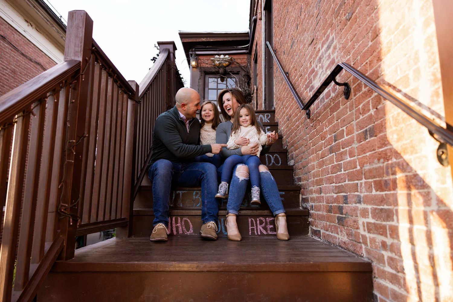 Family sitting on brick steps during outdoor photo session.