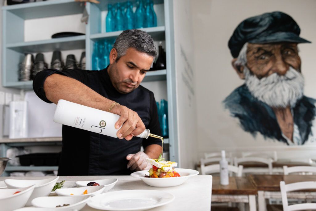 A collection of hands plating gourmet dishes in a professional kitchen shows culinary expertise in action.