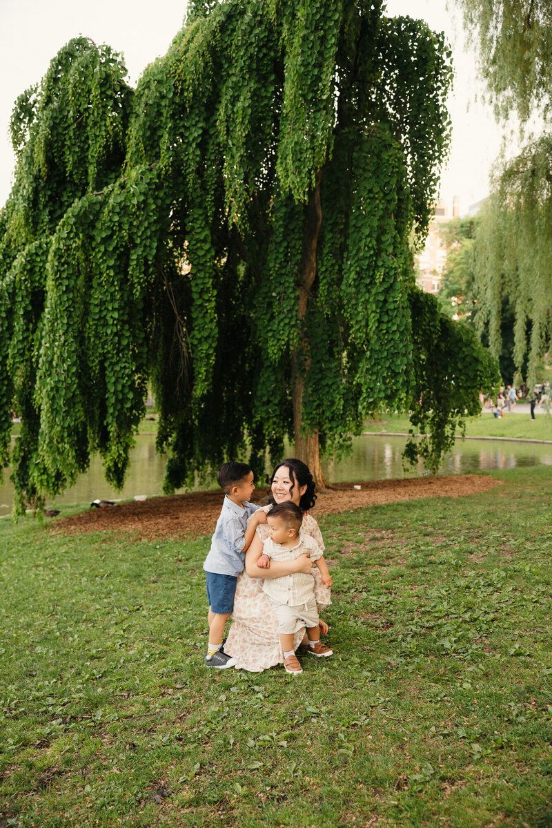 Family portraits under cascading willow tree branches in a park.