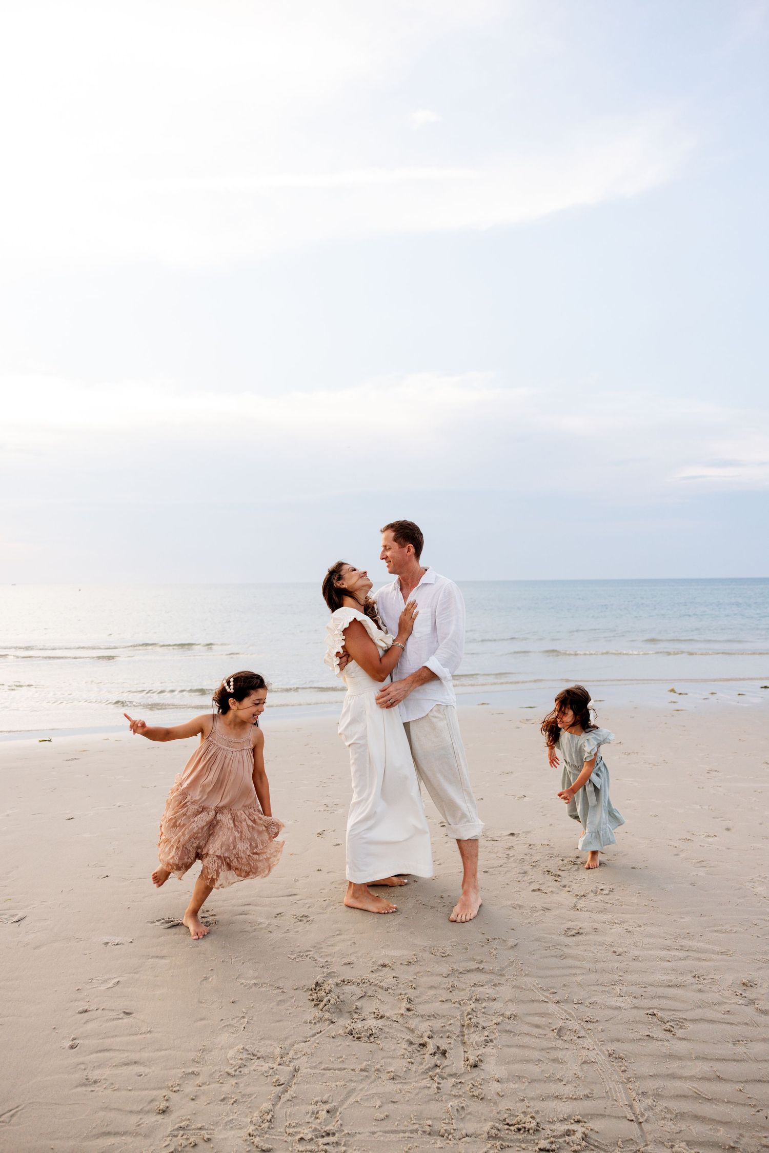 Playful couple dances together on sandy beach at sunset creating romantic moments by the ocean.