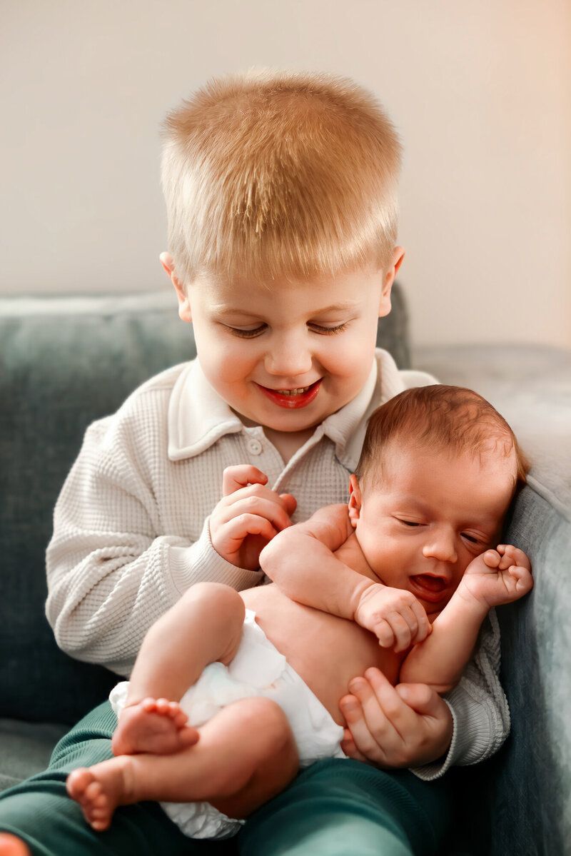 Two siblings share a sweet bonding moment on a dark green couch.