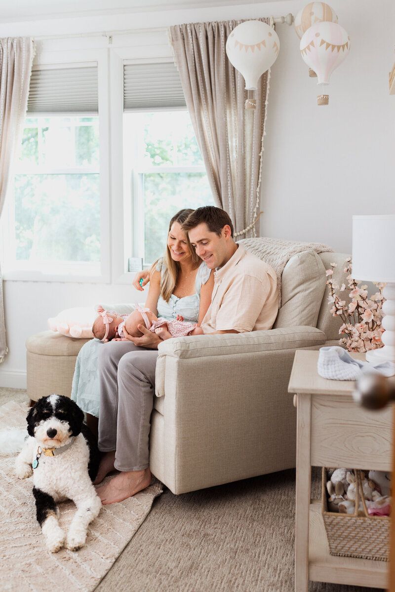 A cozy living room scene with a couple on a beige couch and their black and white dog sitting nearby.
