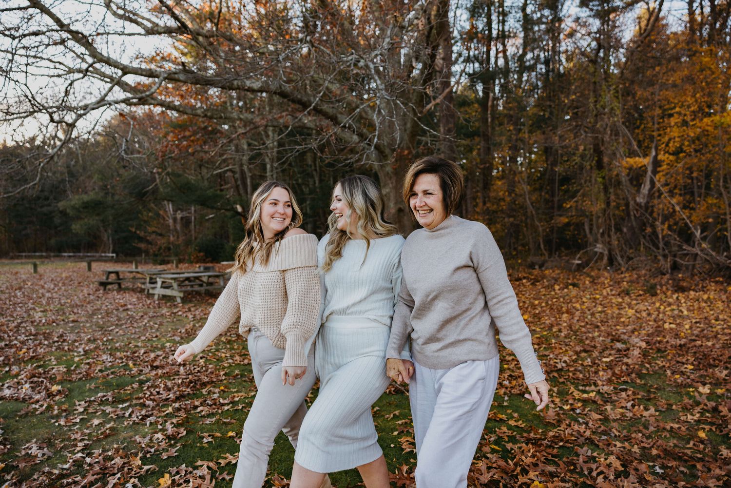Group wearing matching white sweaters walking through autumn forest.