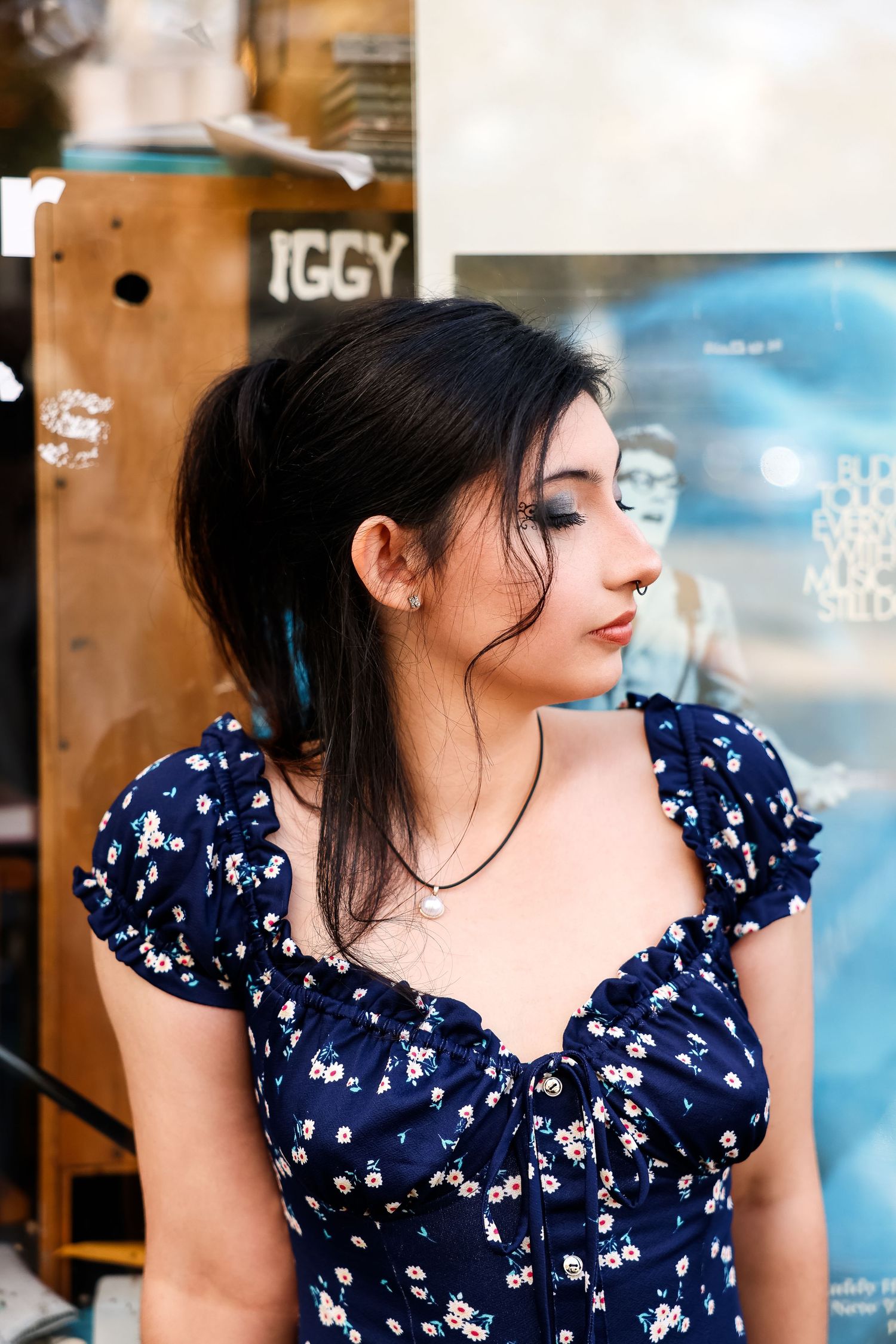 Side profile portrait of someone wearing a navy floral dress with puff sleeves against a blurred background.