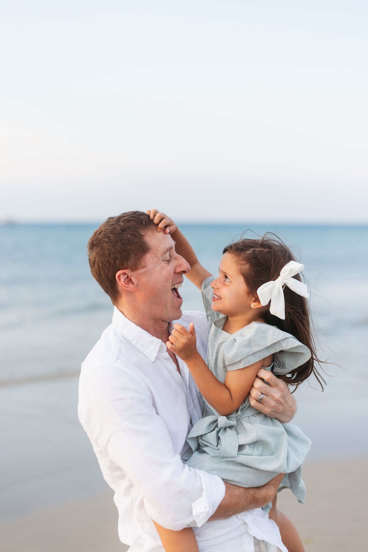Joyful moment captured as two people share laughter and embrace on a peaceful beach at sunset.
