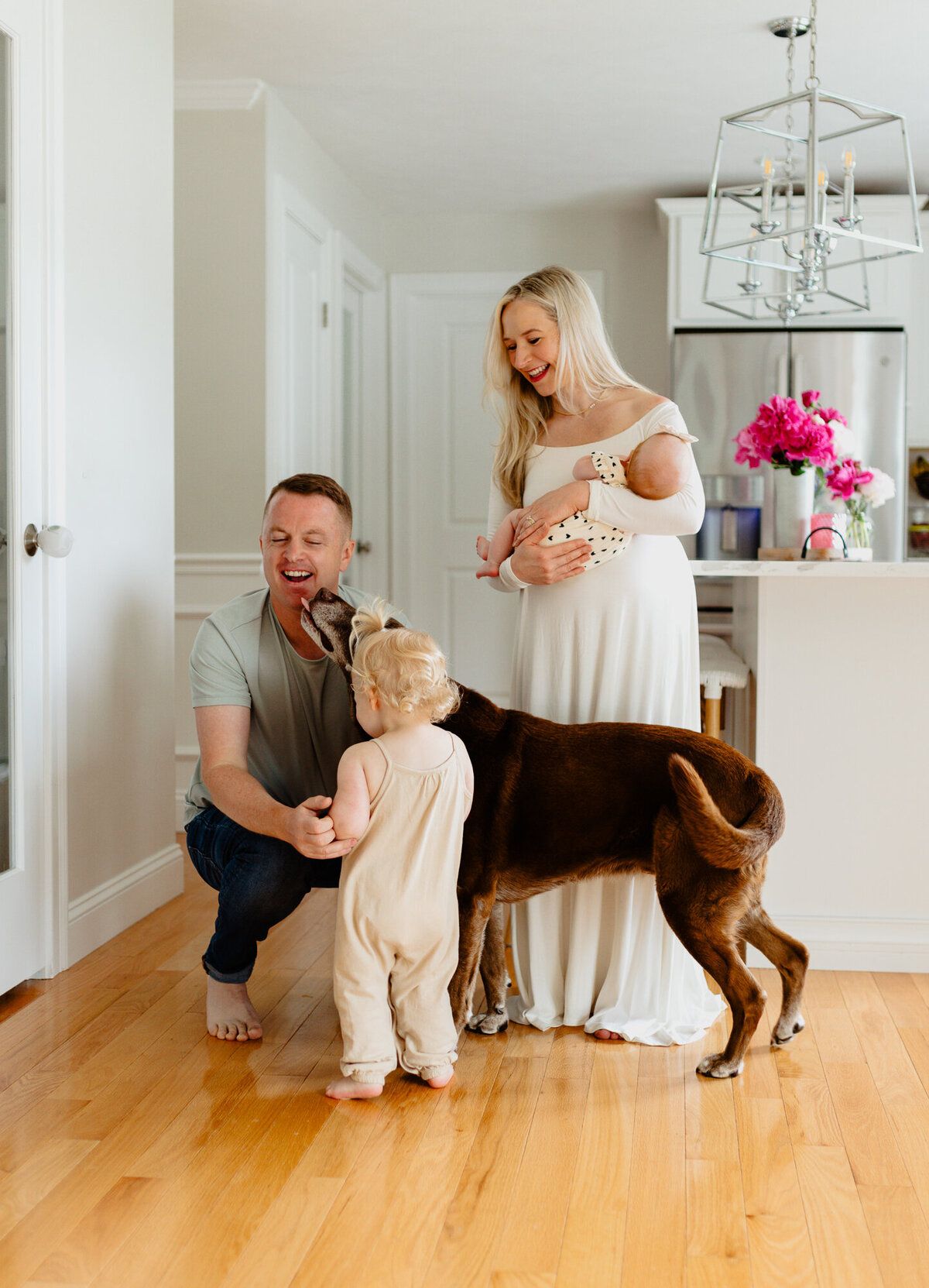 Candid family moments with a brown dog on hardwood floors in a bright white home interior.