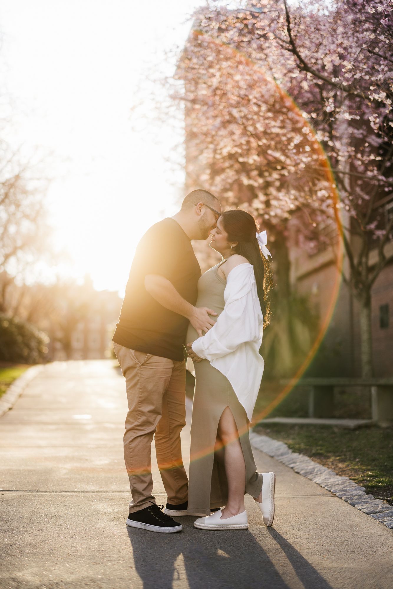 A romantic proposal moment captured under blooming cherry blossom trees at sunset.
