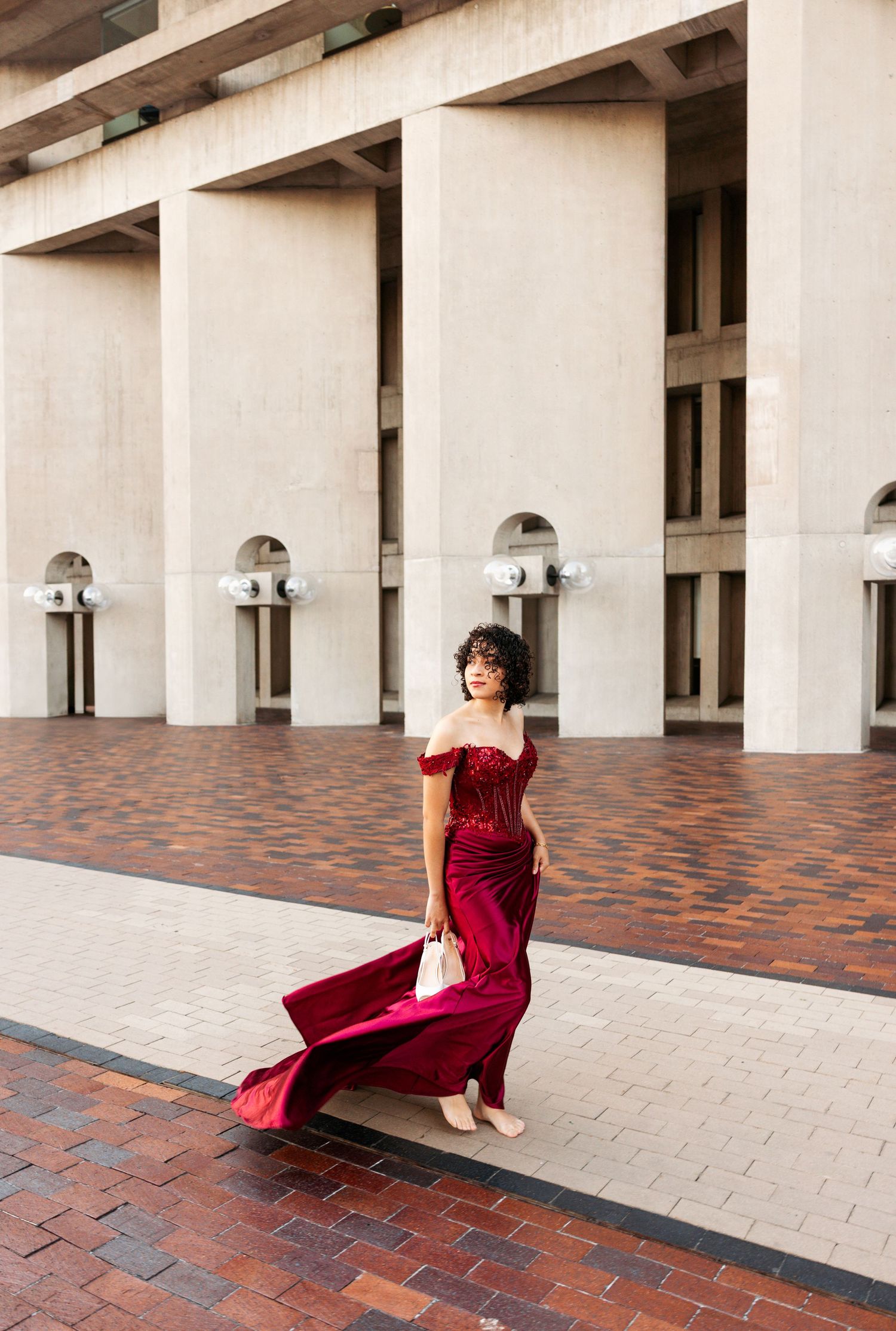 A series of five photos showing a person in a flowing red dress posing gracefully against white columns and brick pavement.