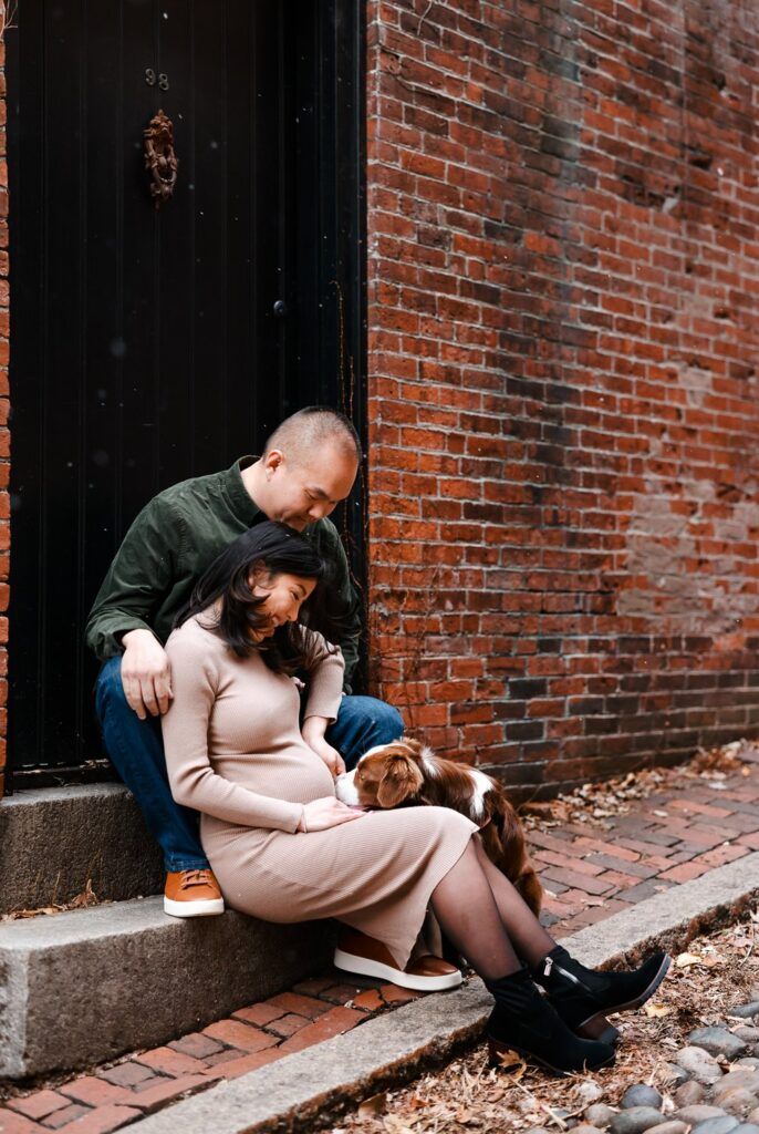 A couple sits intimately on brick steps during autumn, with fallen leaves scattered around the ground.