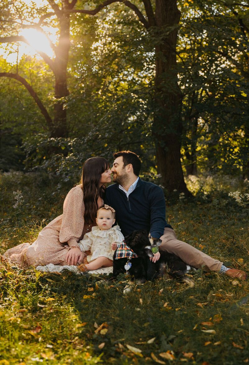 Family having intimate moment on grass during golden hour sunset.