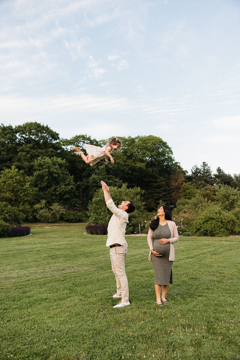 Playful couple interacting on a grassy hill during golden hour photography session.