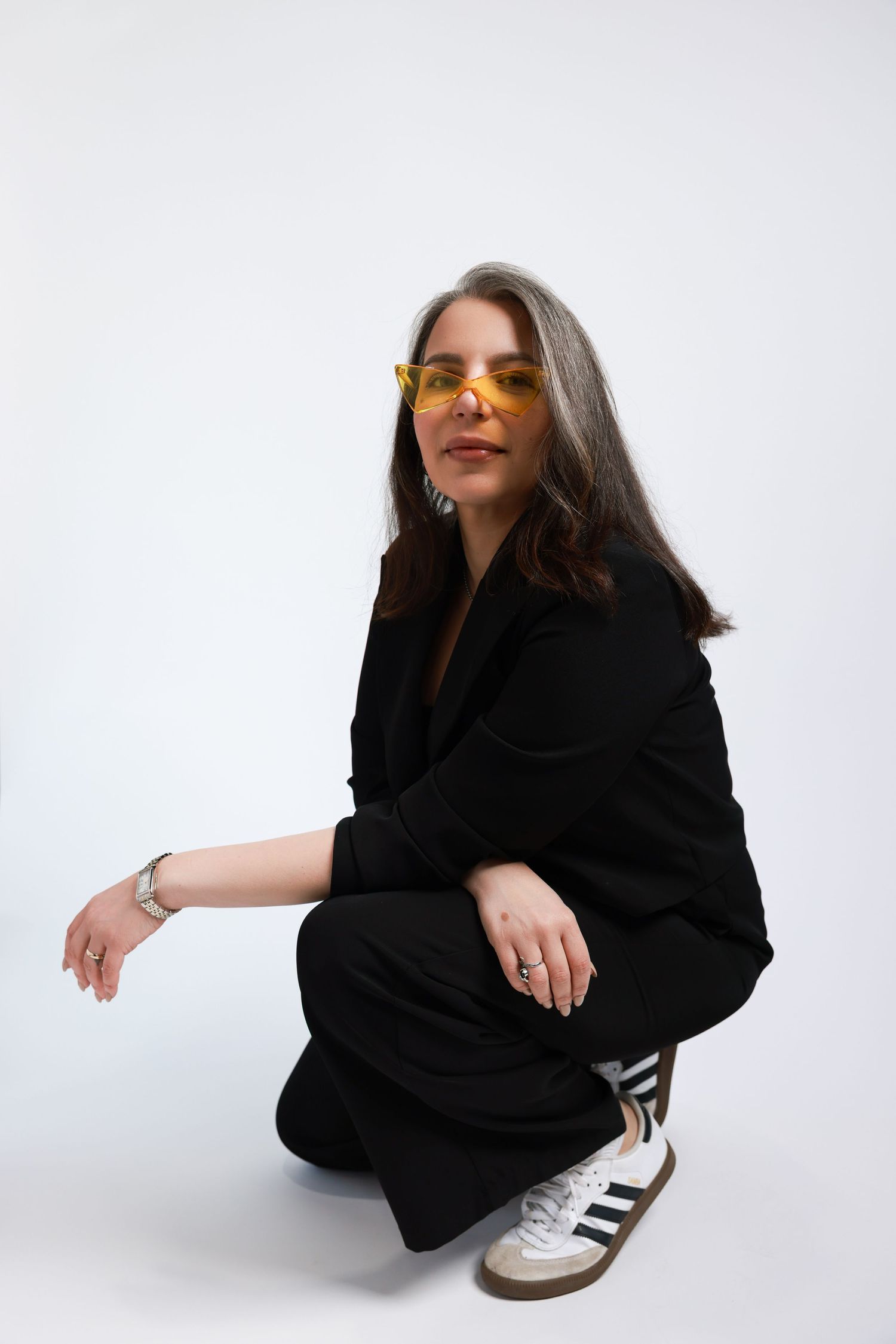 A person in a black sweater strikes different playful poses while sitting on a white background.