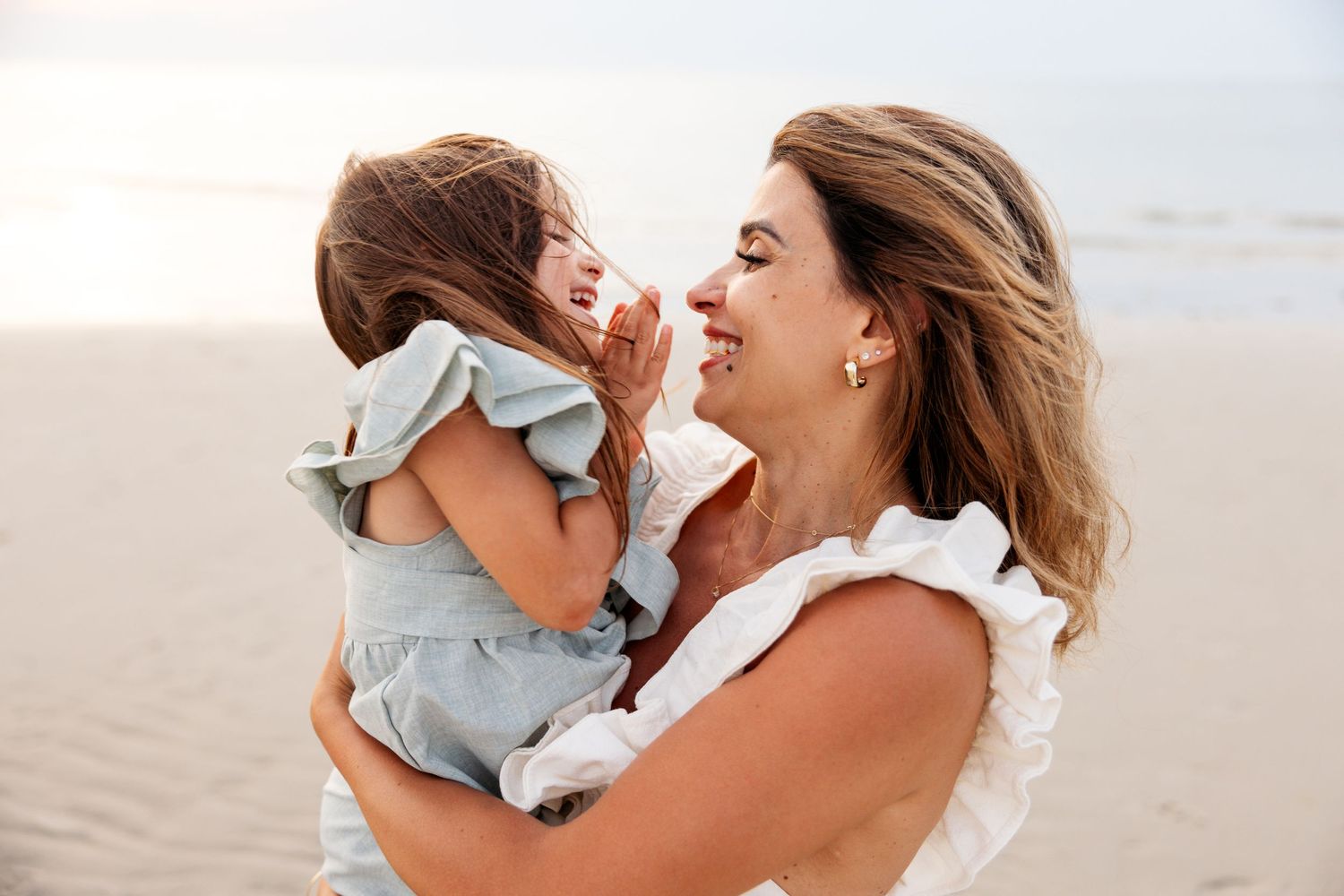 Group of beachy lifestyle photos showing tender moments between mother and baby on sandy shoreline at sunset.