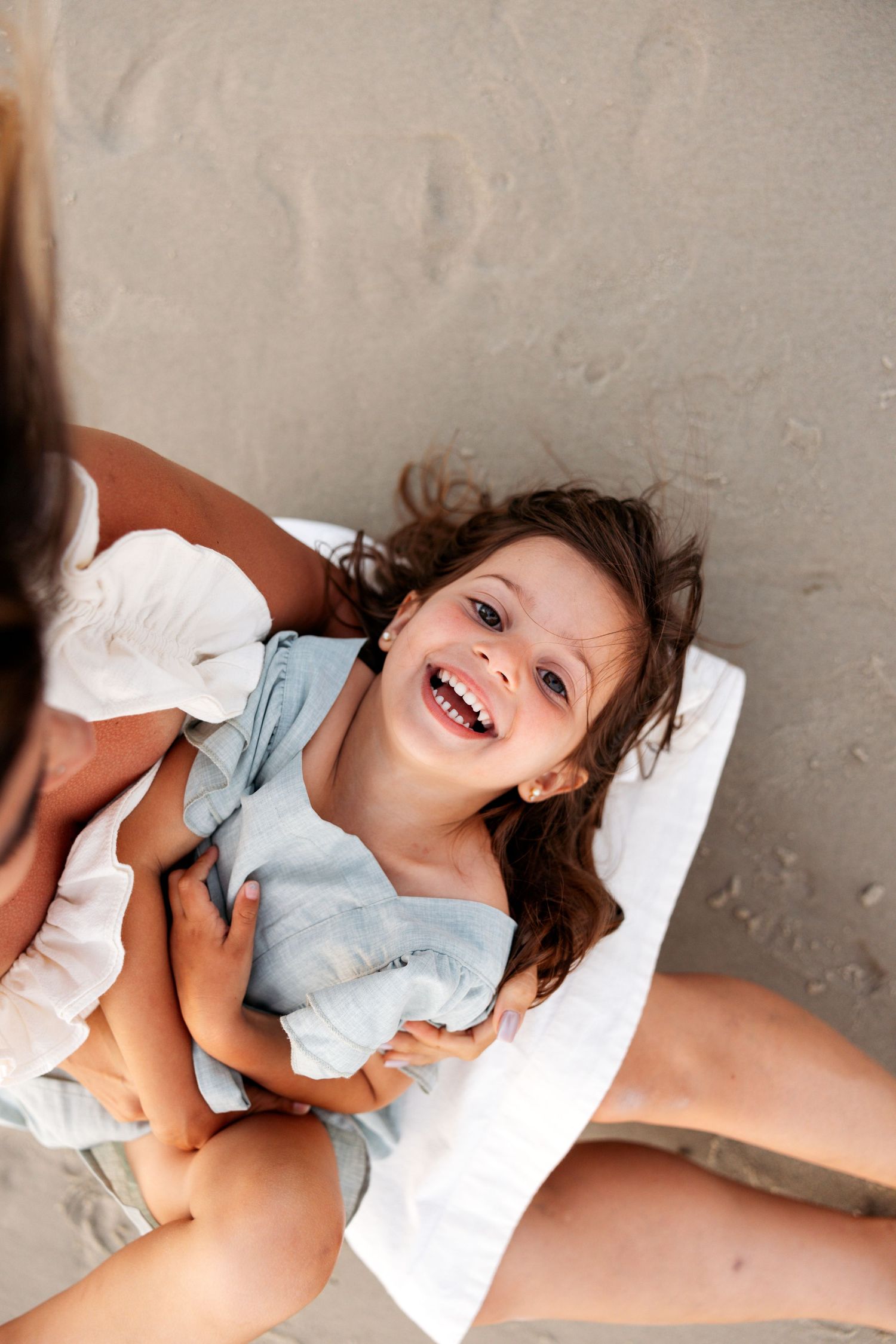 A series of joyful candid moments showing playful expressions while lying on a light colored surface.