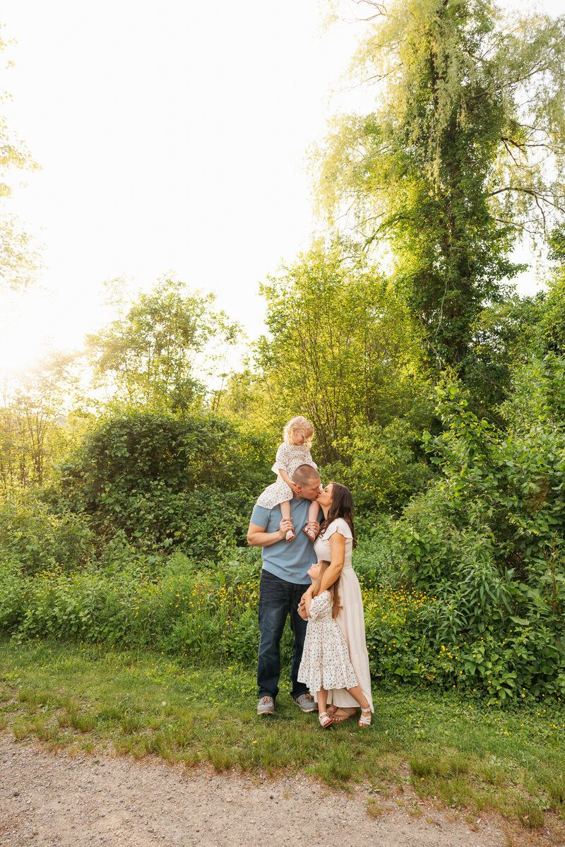 Family sharing tender moments together in natural outdoor setting during golden hour.