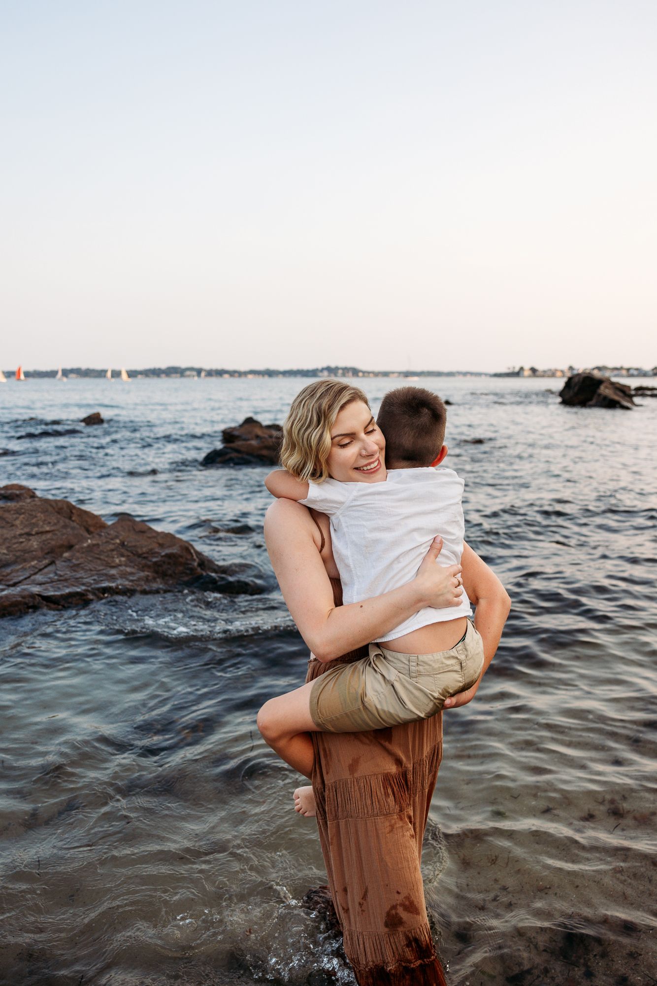 Playful couple embraces in the ocean water during sunset, creating a romantic seaside moment.