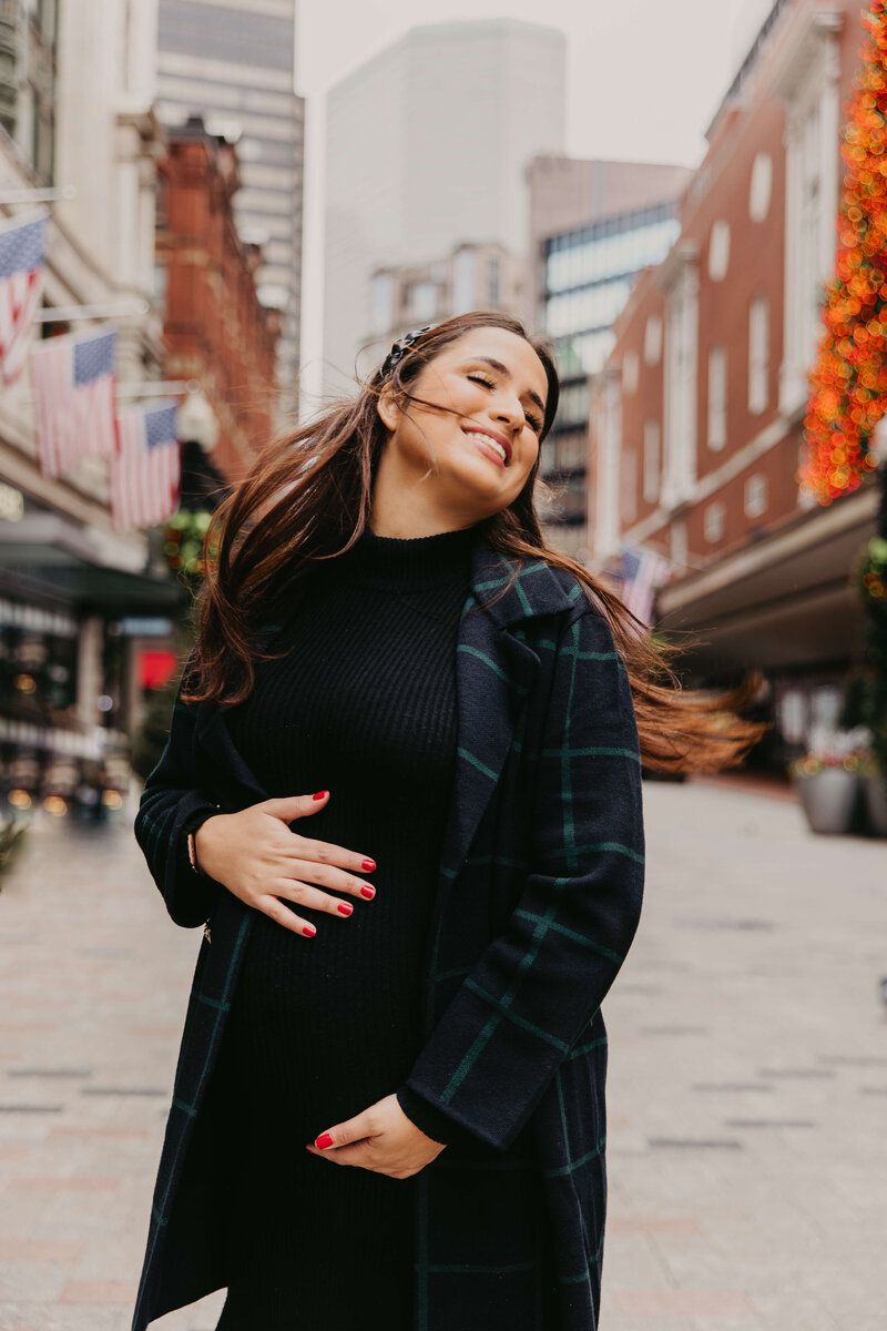 Woman dancing and twirling joyfully on a city street decorated with autumn leaves.