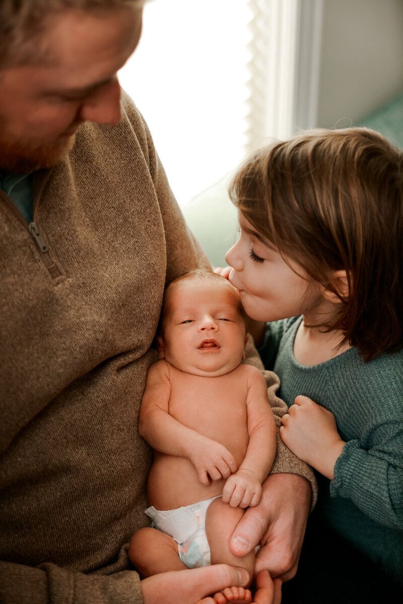 An intimate family moment showing a sleeping baby receiving gentle affection.