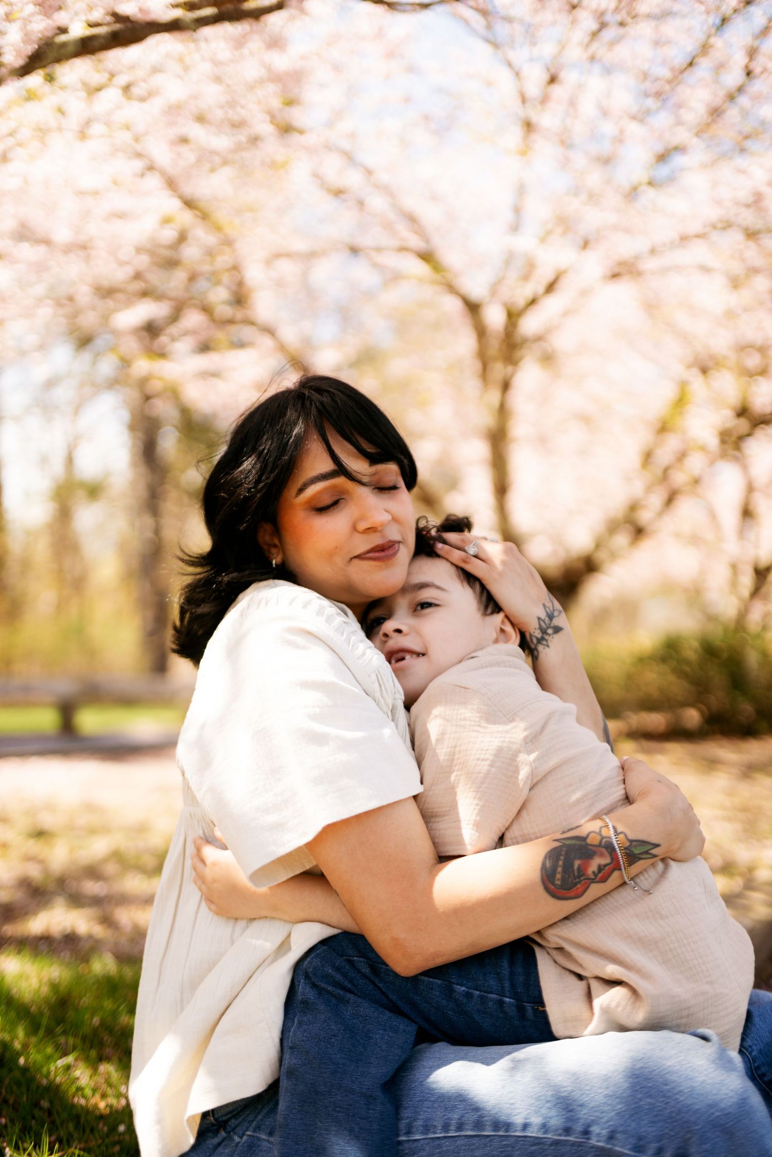 Intimate portrait showing gentle affection and embraces under pink cherry blossom trees.