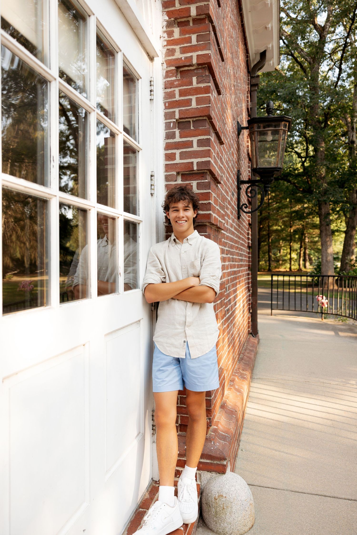 Three connected images show a person in a white shirt and blue shorts posing along a brick building with large windows.