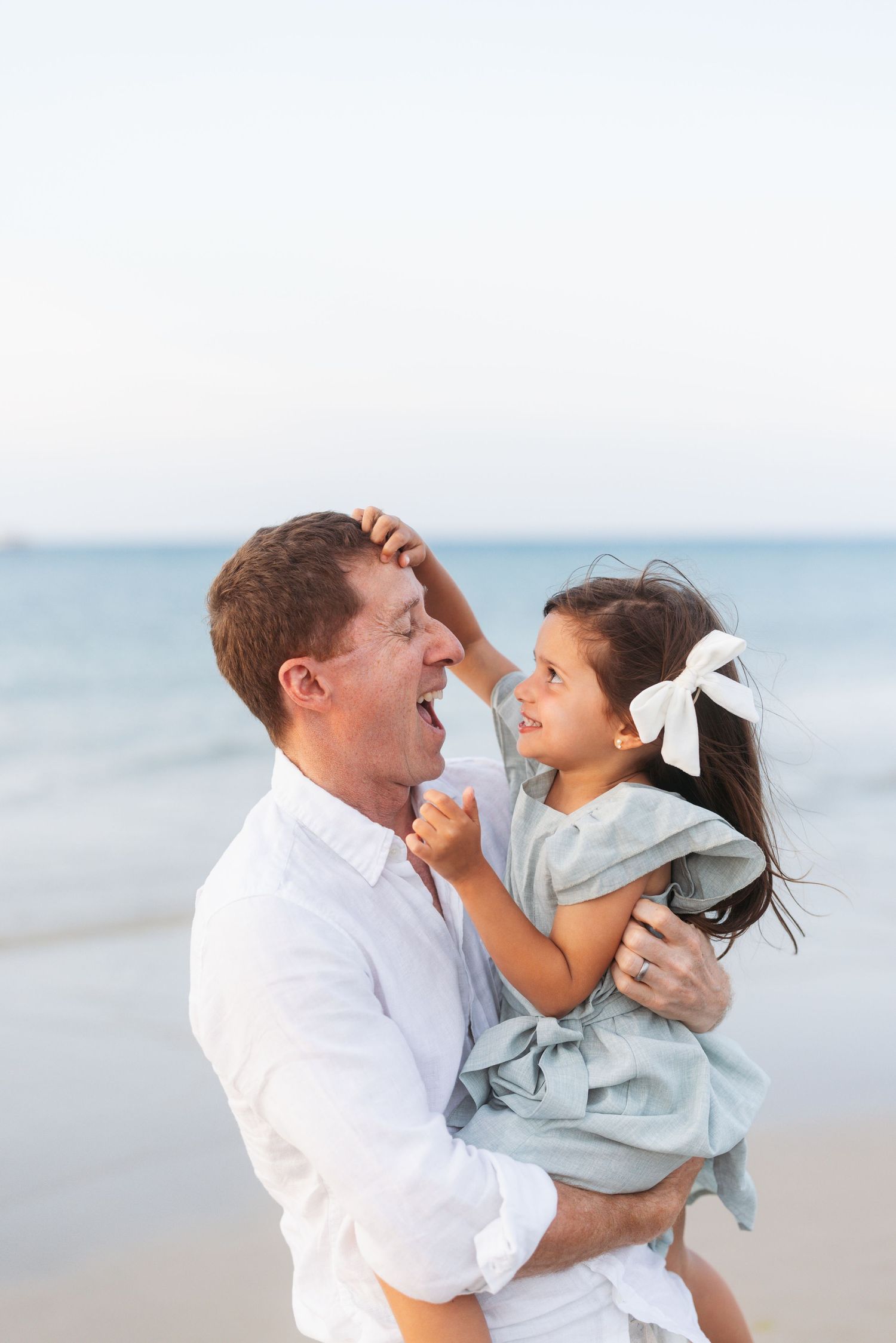 Playful moments shared between parent and child laughing together on a peaceful beach.